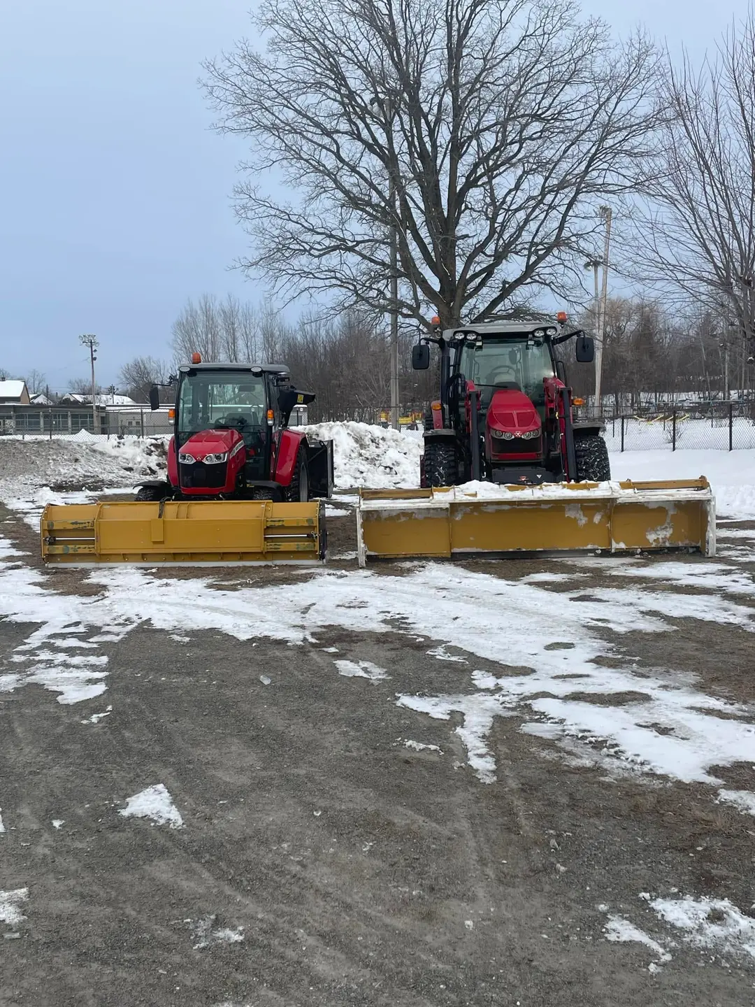 Les deux tracteurs de déneigement de l'Entreprise SME côte à côte dans la neige, lames jaunes à l'avant