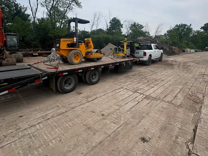 Rouleau compacteur jaune chargé sur une remorque plateau