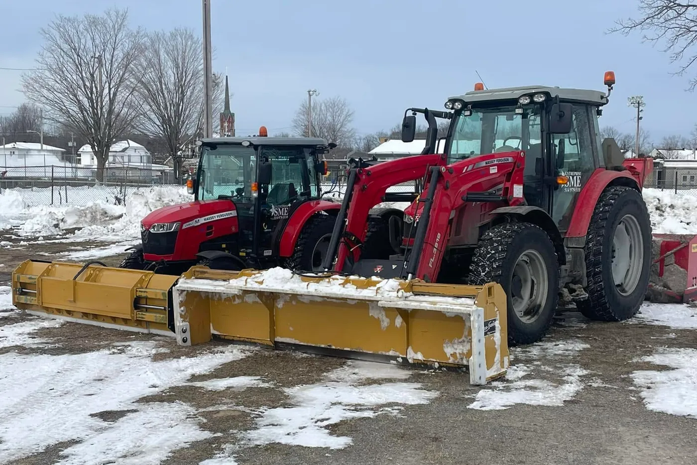 Les deux tracteurs de déneigement de l'Entreprise SME côte à côte dans la neige, lames à l'avant