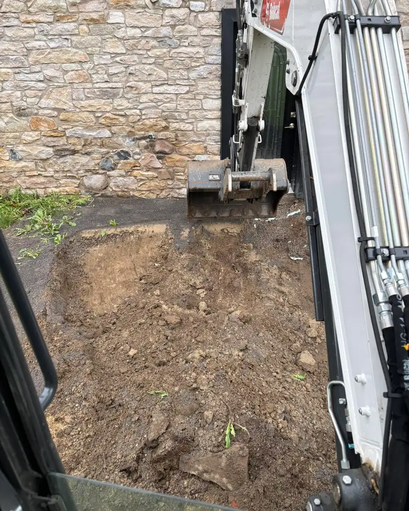 Godet de la pelle en train de creuser le long d'un mur de fondation en pierre
